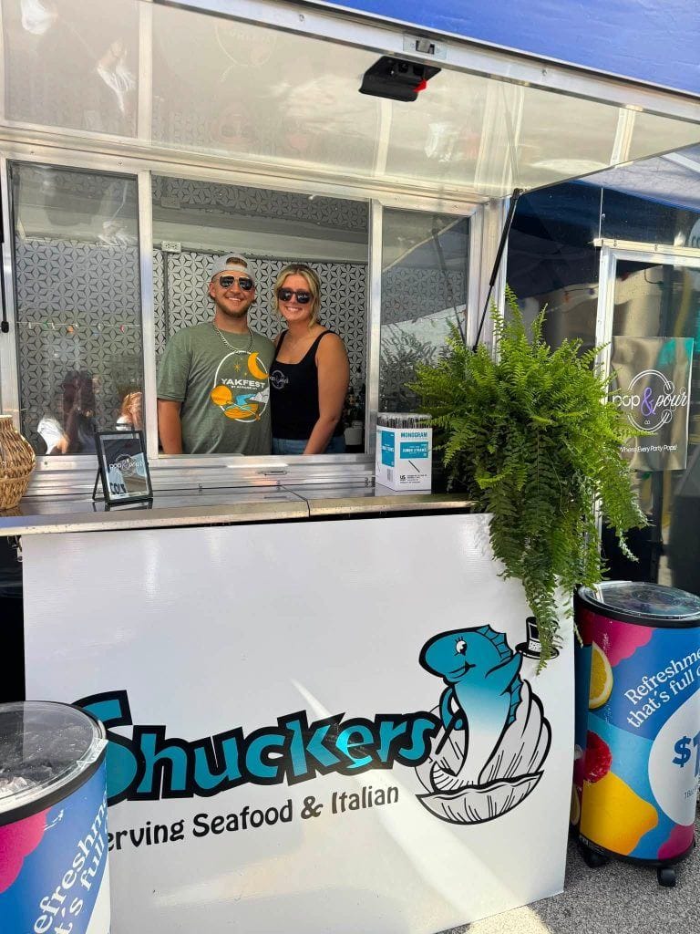 Pop & Pour Co. staff serving guests from the Shuckers beverage trailer